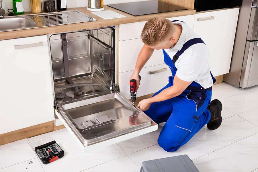 Technician repairing a dishwasher in a kitchen