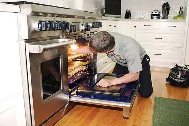 Technician repairing an oven in a kitchen